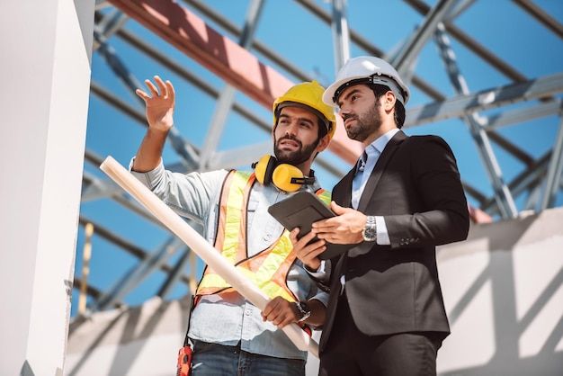 Free Photo _ Civil engineer and construction worker manager holding digital tablet and blueprints talking and planing about construction site cooperation teamwork concept